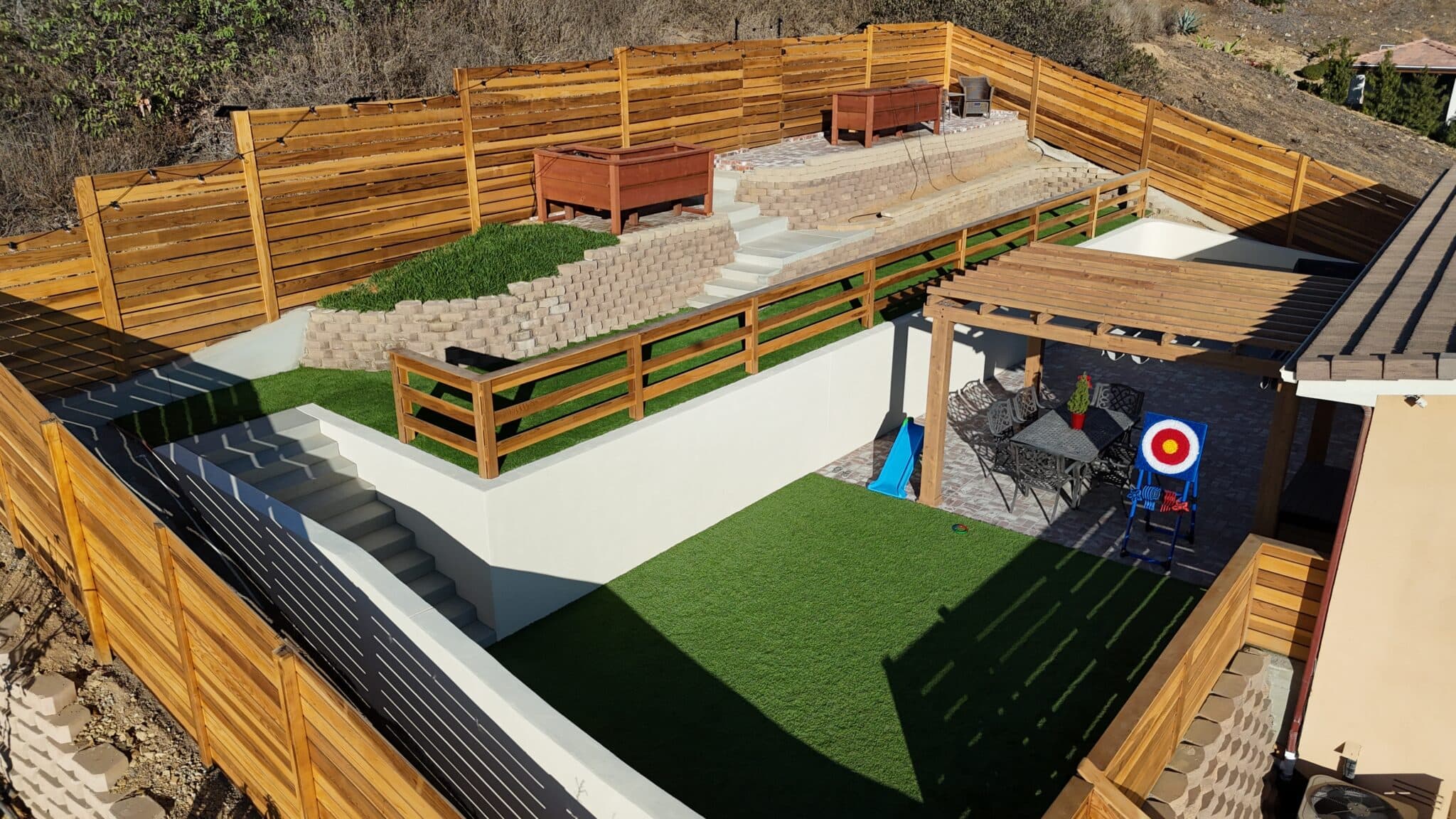 Outdoor patio with black horizontal privacy fence and hanging string lights