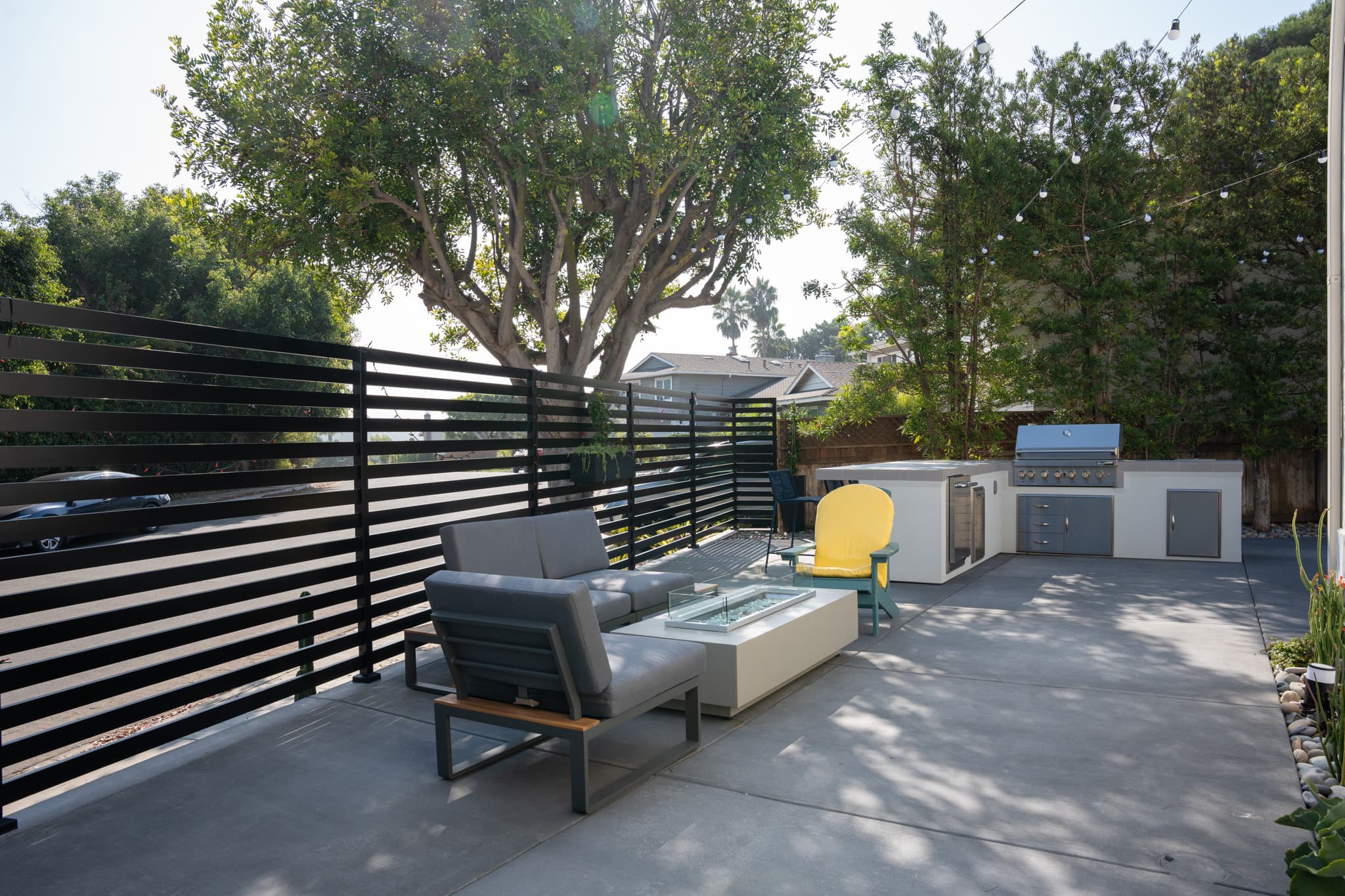 Modern outdoor patio with privacy fencing, built-in grill, and lounge seating.