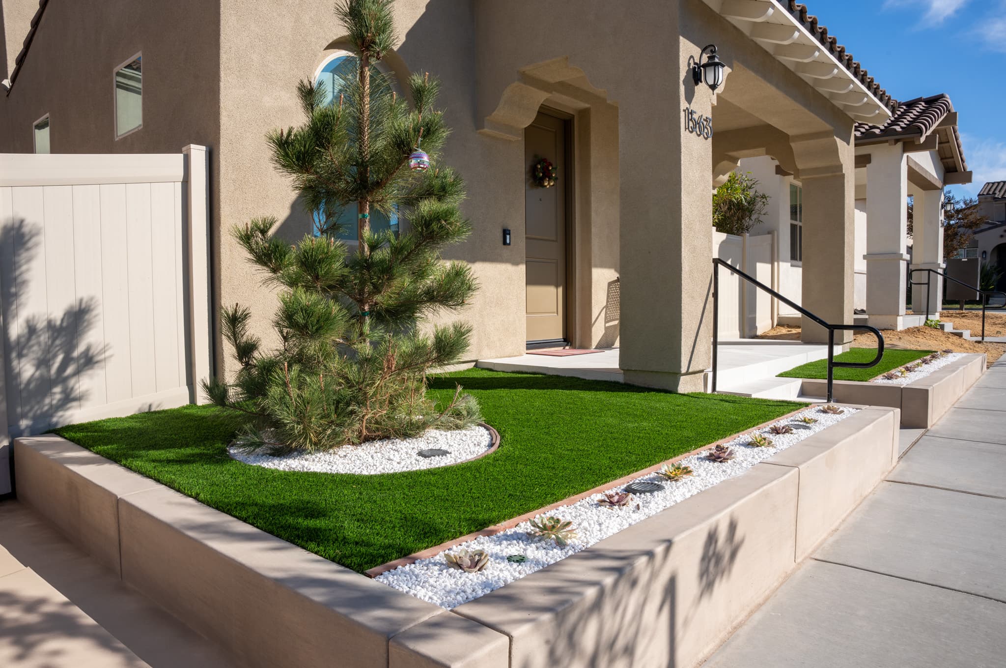 Modern front yard remodel featuring artificial grass and elegant retaining walls.